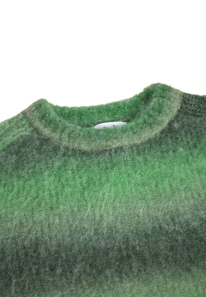 Close-up of a green sweater with a gradient effect on a white background