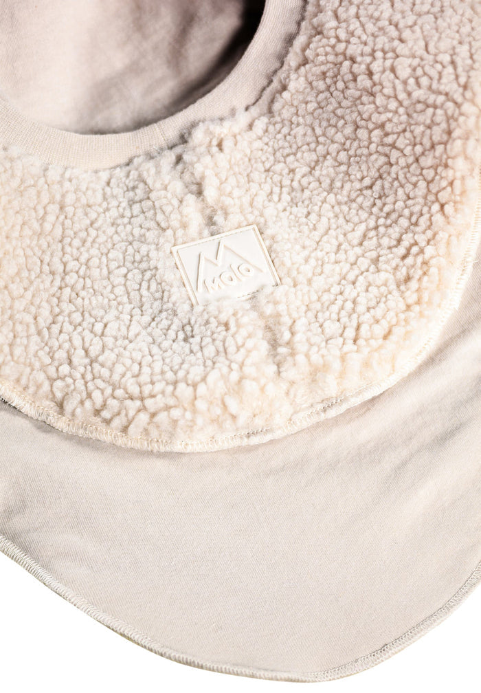 Close-up of a beige sherpa-lined product with a brand logo.